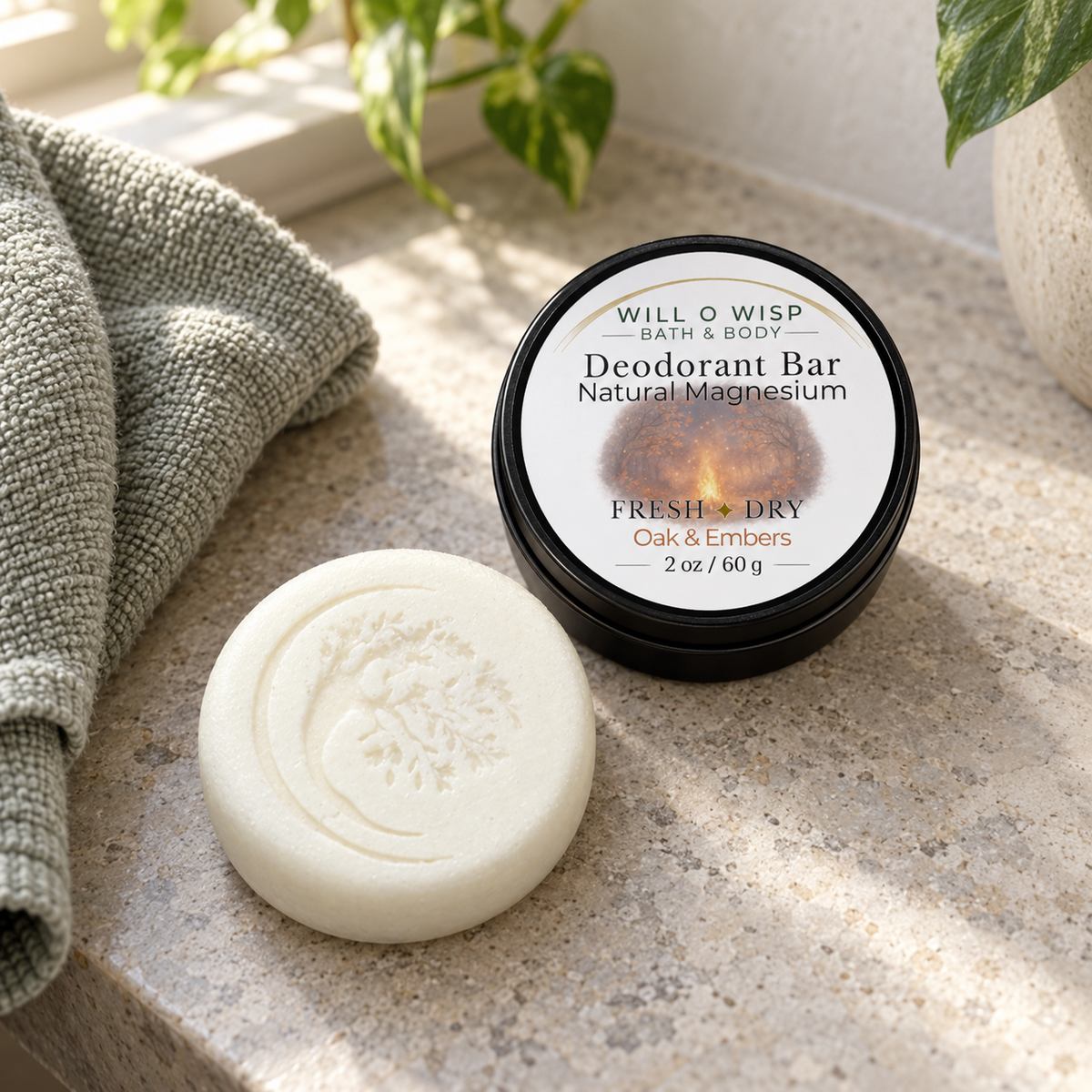 WILL O WISP BATH & BODY Oak & Embers magnesium deodorant bar with embossed tree design next to its black storage tin.